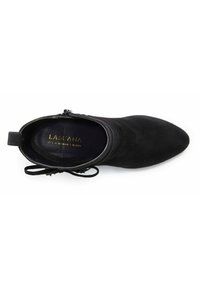 Stivale alla caviglia in suede nero con punta affusolata, chiusura con zip e dettagli di pizzo decorativi sulla caviglia. L'interno presenta il logo del marchio.