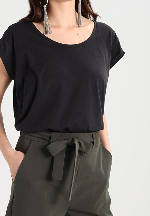 T-shirt noir à manches courtes avec un col rond, associé à un pantalon taille haute vert olive avec un détail de ceinture nouée.