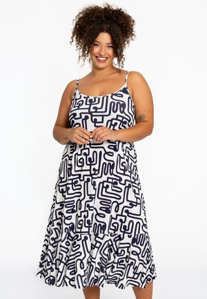 Robe à motifs avec des bretelles spaghetti, présentant un design abstrait bleu marine sur fond blanc, un ourlet évasé et un tissu léger.