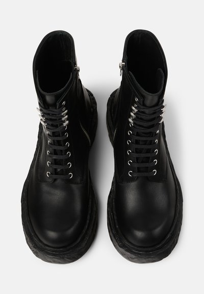 Black leather ankle boots with a chunky sole, featuring silver eyelets, front lacing, and a zip closure on the side.