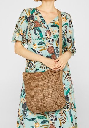 Borsa a tracolla marrone intrecciata con superficie testurizzata, caratterizzata da un design semplice e morbido e una tracolla. Decorata con un piccolo logo.