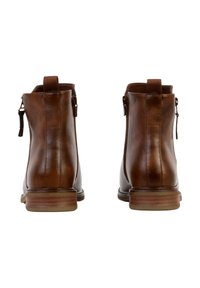 Paire de bottines en cuir marron avec languettes de tirage et fermetures éclair latérales, vues de dos sur un fond blanc.