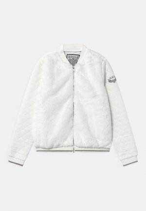 Veste bomber blanche avec un corps en fourrure, des manches blanches matelassées, une fermeture éclair argentée et un logo sur la manche gauche. Texture douce dans l'ensemble.