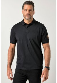 Musta pehmeästä kankaasta valmistettu poolopaita, jossa on kolmen napin läpyskä, kirjailtu logo ja koristeellinen merkki hihassa.