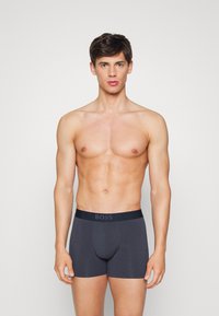 Boxer briefs cinza escuro com uma faixa elástica rotulada "BOSS", apresentando um design ajustado e textura suave.