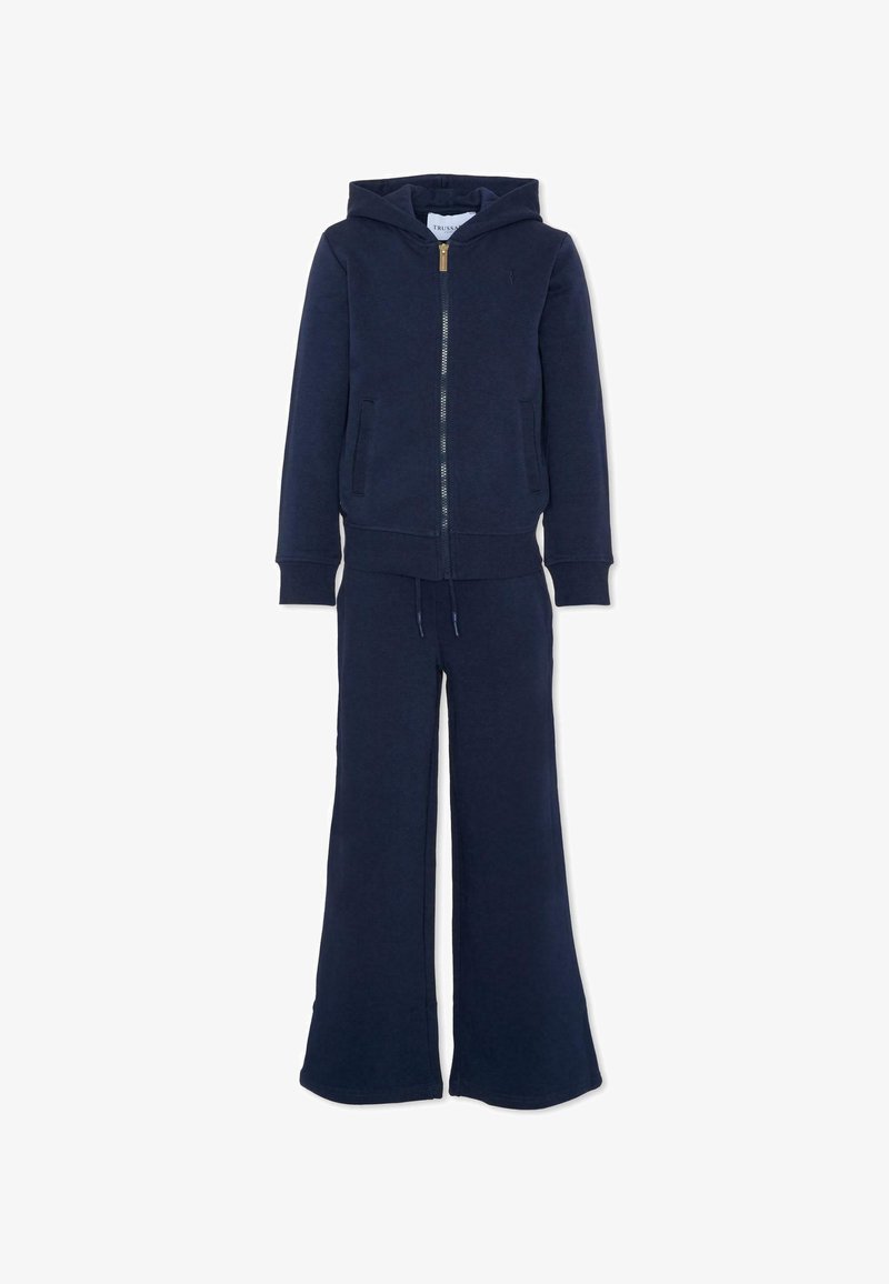 Haut à capuche bleu marine avec fermeture éclair frontale et pantalon large assorti, présentant des poches et une taille à cordon, exposé sur fond blanc.