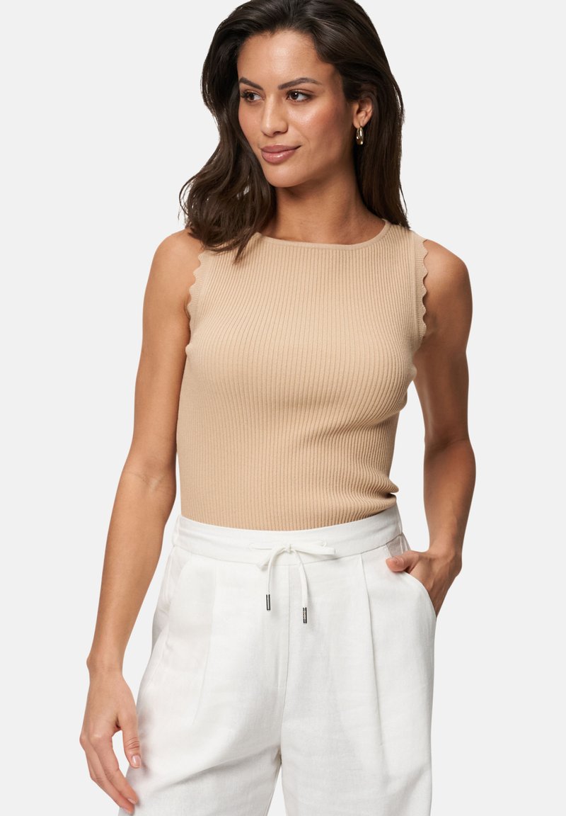 Top sans manches beige à côtes avec des bords festonnés. Fabriqué en tissu lisse, design ajusté. Assorti à un pantalon blanc taille haute.