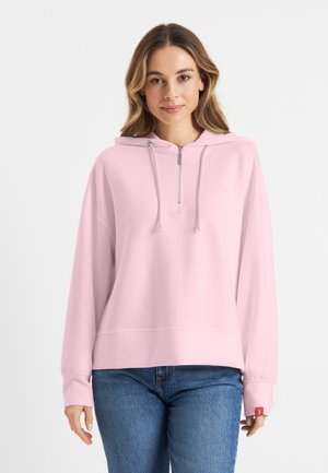Lichtroze hoodie met een rits aan de voorkant, losse pasvorm en geribbelde manchetten. Heeft een klein logo op de borst en een accentlabel op de mouw.