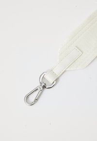 Cinghia bianca in tessuto texturizzato, con attacco in pelle e un moschettone in metallo argento per un fissaggio sicuro. Design semplice e funzionale.