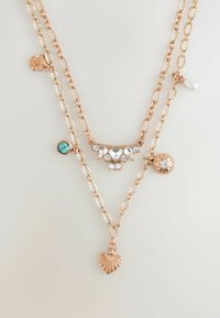 Schichtkettenanhänger in Roségold mit verschiedenen Charms, darunter ein Herz, ein Türkisstein und klare Edelsteine. Strukturierte Kettenglieder und Akzente.