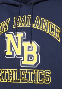 Sudadera azul marino con la inscripción "NEW BALANCE ATHLETICS" y "NB" en letras amarillas y blancas en negrita. Incluye cordones en el cuello.