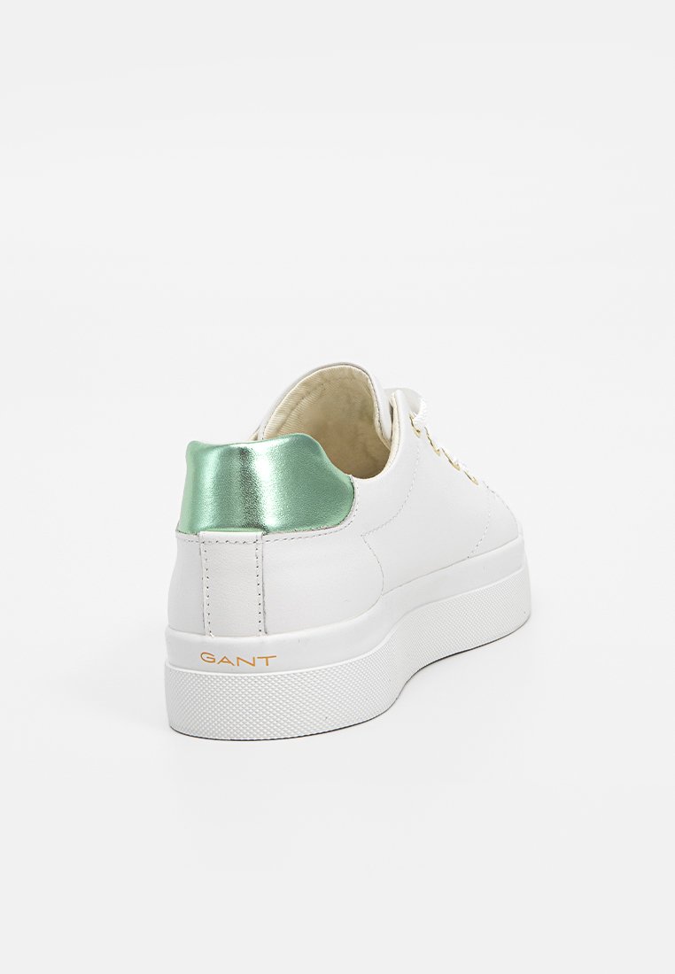 Weiße Ledersneaker mit einem grünen metallischen Akzent an der Ferse und einer strukturierten Gummisohle. Mit goldener Markenprägung an der Seite.