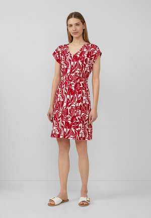 Rot-weiß gemustertes Kleid mit kurzen Ärmeln, V-Ausschnitt, tailliertem Schnitt und knielangem Saum. Kombiniert mit weißen Riemchensandalen.