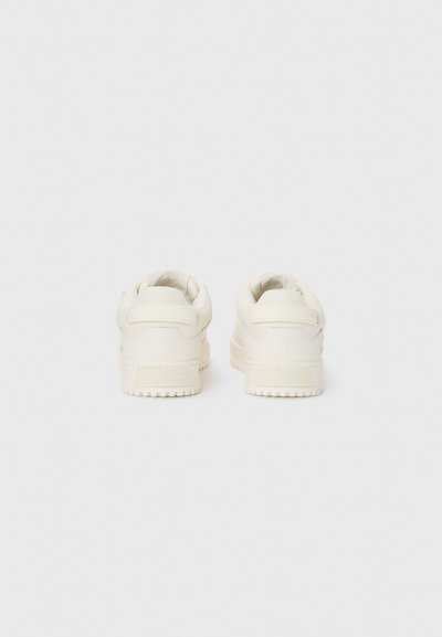 Sneaker bianco con tomaia in pelle liscia, punta arrotondata, suola in gomma texturizzata, colletto imbottito e branding minimale sul tallone.