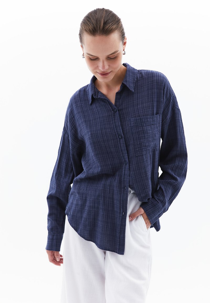 Mörkblå rutig skjorta med knappar, lång ärm, bröstficka och avslappnad passform, tillverkad av en strukturerad tyg.