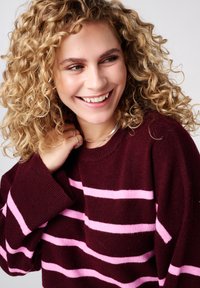 Bordeauxrode trui met horizontale roze strepen, gemaakt van zacht gebreide stof. Heeft een ronde hals en verlaagde schoudernaden.