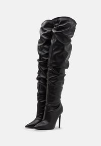 Schwarze Overknee-Stiefel aus glattem Kunstleder mit einem lässigen Design, spitzem Absatz und hohen Stiletto-Absätzen.