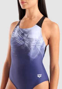 Bikinibroekje in een verloop van blauw naar zwart, met een geometrisch patroon en logo op de voorkant. Gemaakt van rekbaar materiaal met een racerback-ontwerp.