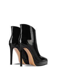 Stivali alla caviglia in vernice nera con punta affusolata, tacco a stiletto di 12 cm e piattaforma anteriore. Presentano una chiusura con zip sul retro.
