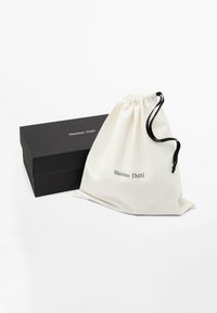 Sac à poussière en coton crème avec cordon de serrage noir et logo imprimé "Massimo Dutti". Boîte rectangulaire noire avec accents dorés.
