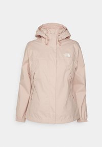 Giacca impermeabile rosa con cappuccio, polsini elasticizzati e due tasche laterali. Presenta un logo sul petto e una superficie di tessuto liscia e morbida.