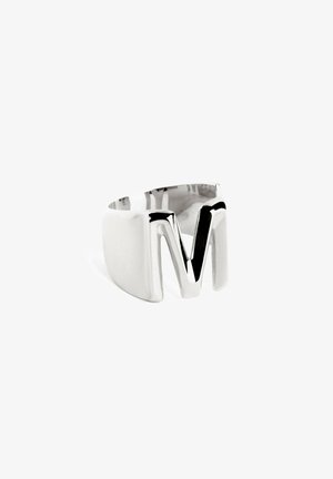 Bague en argent avec une large bande, arborant un design en 'M' angulaire et proéminent. Texture lisse avec finition polie et intérieur noir contrastant.