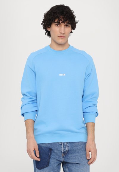 Sudadera de color azul claro hecha de una mezcla de algodón, con cuello redondo, puños acanalados y un pequeño logo blanco en el centro.