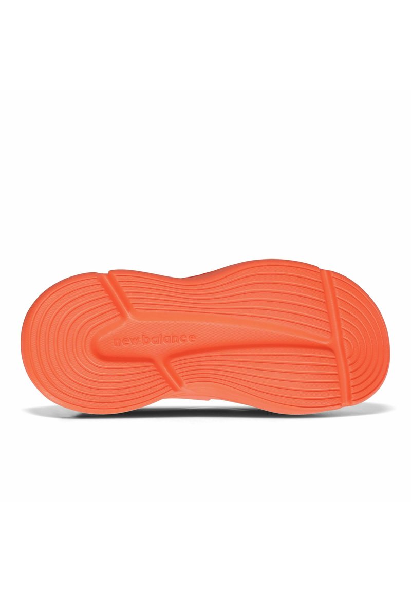 Orangefarbene Gummisohle eines Sneakers mit strukturierten Wellenmustern und Rillen. Mit eingeprägtem "New Balance"-Logo an der Seite.