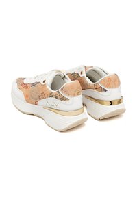 Sneakers bianchi con un pannello a tinta unita rosa pallido decorato con timbri di viaggio, dettagli in oro sul tallone e una suola spessa bianca.