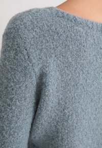 Jasnoniebieski sweter dzianinowy o teksturowanym, puszystym wykończeniu, z okrągłym dekoltem i luźnym krojem.