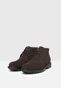 Stivaletti in suede marrone con punta rotonda, stringhe e suole in gomma nera. Design pulito con dettagli di cucitura minimi. Adatti per un abbigliamento casual.