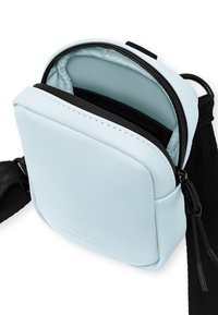 Borsa a tracolla in ecopelle azzurro chiaro con chiusura a zip superiore, interno nero e tracolla regolabile. Design compatto e di forma quadrata.