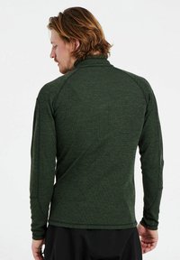 Grüne langärmlige Bluse aus strukturiertem Stoff. Verfügt über einen hohen Kragen und Raglanärmel. Einfaches Design mit kontrastierenden Nähdetails.