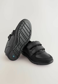 Scarpe nere con una combinazione di pelle liscia e tessuto testurizzato, dotate di due cinturini regolabili in Velcro e una suola in gomma con motivo.
