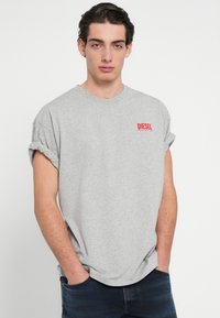 Hall hallist puuvillast T-särk, lühikeste keeratud varrukate ja ümmarguse kaelusega. Vasakul rinnal on punane „DIESEL“ logo. Lõdvestunud istuvus.