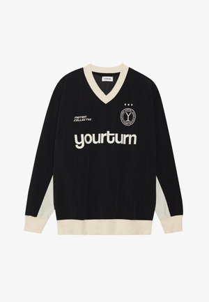 Black long-sleeve jersey with a v-neck, featuring cream accents on the sleeves and hem, and "yourturn" logo in white on the front.