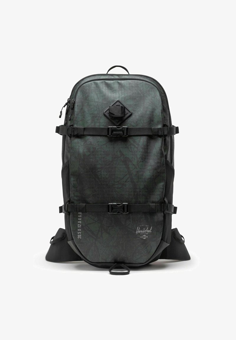 Sac à dos vert à motif avec des accents noirs, doté de sangles réglables, de fermetures à boucle sur le côté et d'une surface texturée. Conception durable.