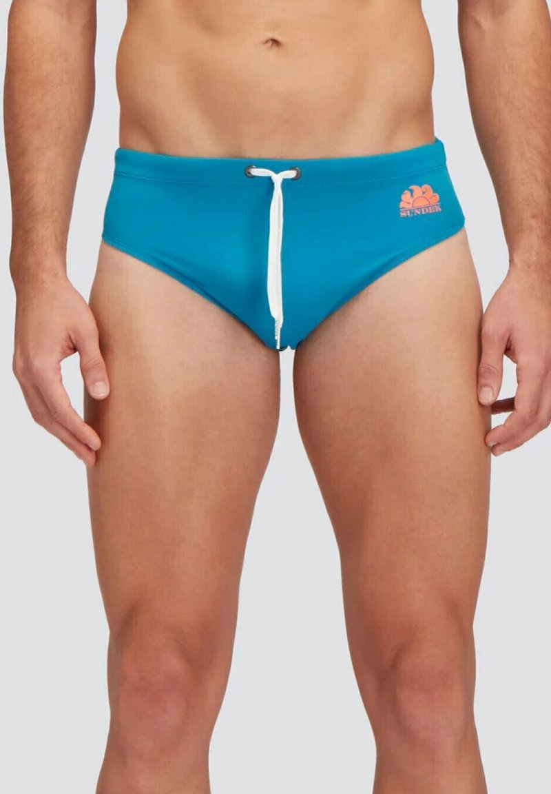 Slip da bagno blu con coulisse bianca, dettagli laterali e un piccolo logo sul davanti. Il materiale sembra liscio ed elastico.