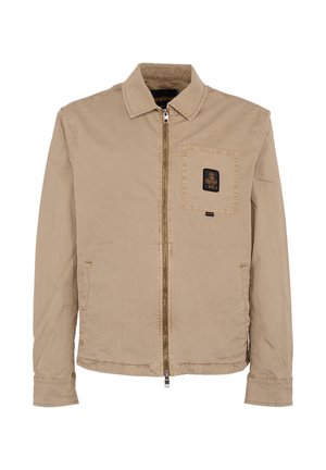 Beige jas met ritssluiting, kraag, lange mouwen, een borstzak aan de voorkant met een zwart label met een gouden embleem, en twee zijzakken.