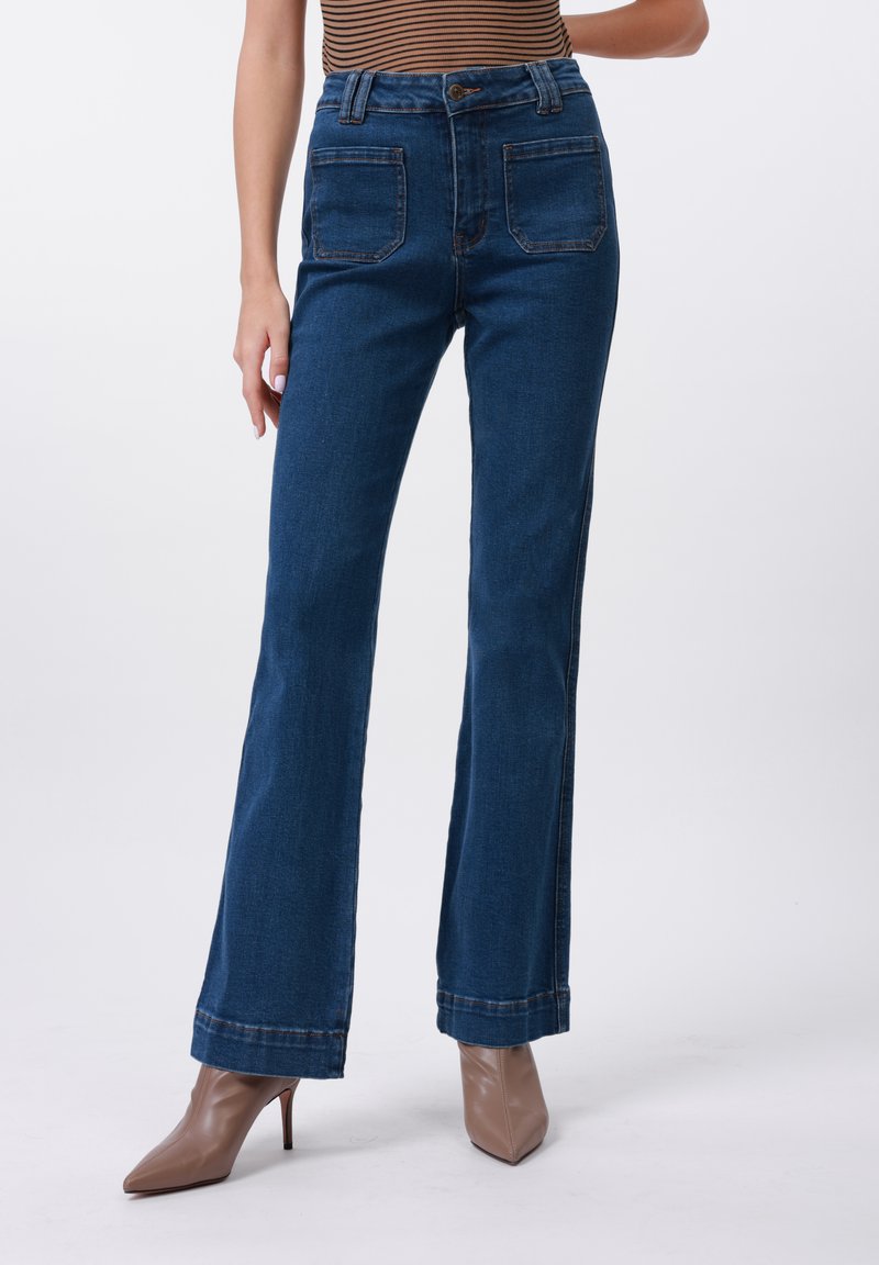 Høytlivte denimjeans i mørkeblått med utsvingte ben, med to baklommer og subtile sømdetaljer ved sømmene.