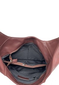 Brązowa skórzana torebka z przestronnym, miękkim wnętrzem wykończonym ciemnoszarym materiałem, licznymi przegródkami i detalami na suwak.