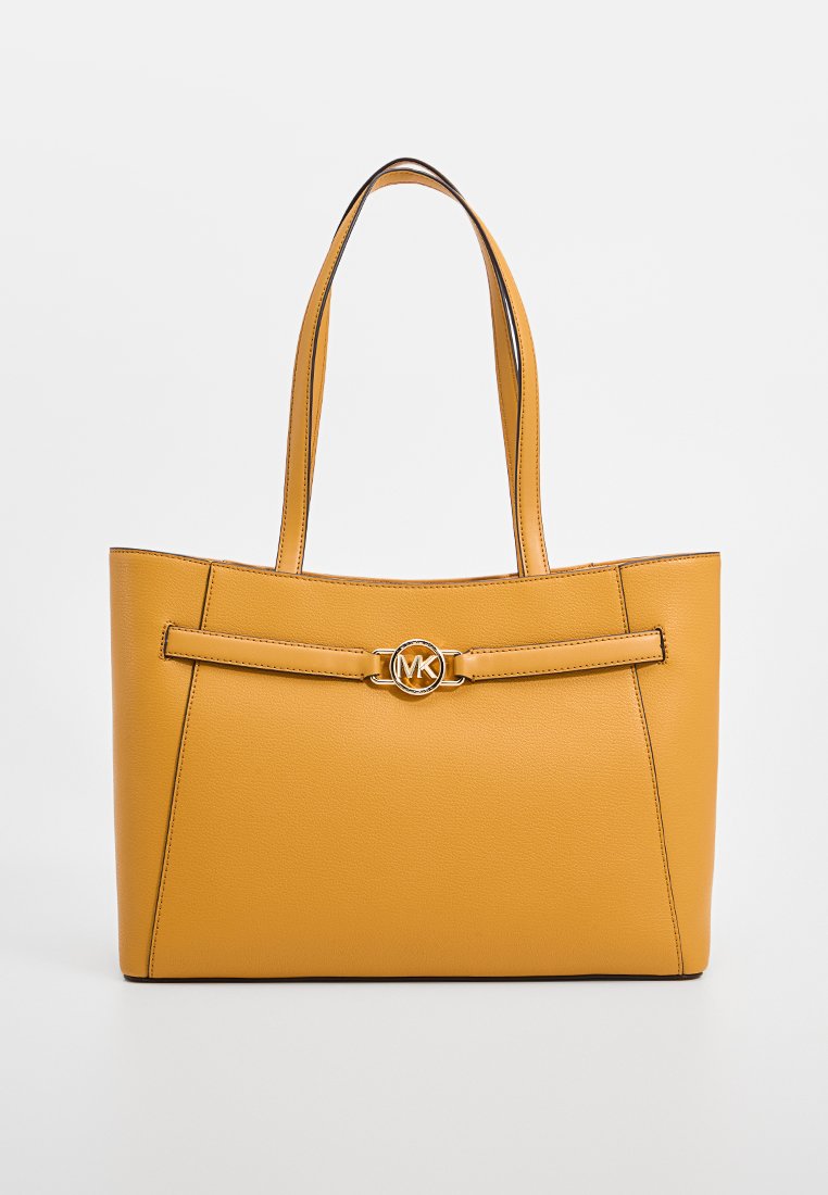 Sac fourre-tout en cuir jaune avec une texture lisse, avec un détail en forme de nœud à l'avant et un logo métallique circulaire. Deux poignées solides.