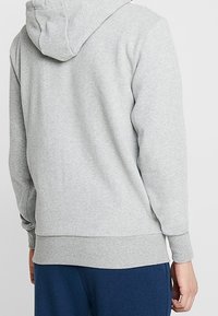 Světlě šedá mikina s kapucí, s žebrovanými manžetami a lemem, vyrobená z měkké látky, s designem klokánkové kapsy na přední straně.