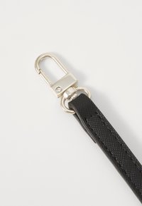 Zwarte nylon riem met een gestructureerd oppervlak, voorzien van een zilveren metalen sluiting en bevestigingshardware. Duurzaam ontwerp voor praktisch gebruik.