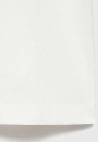 White cotton t-shirt featuring a soft texture, a rounded hem, and stitched accents along the bottom edge for durability.