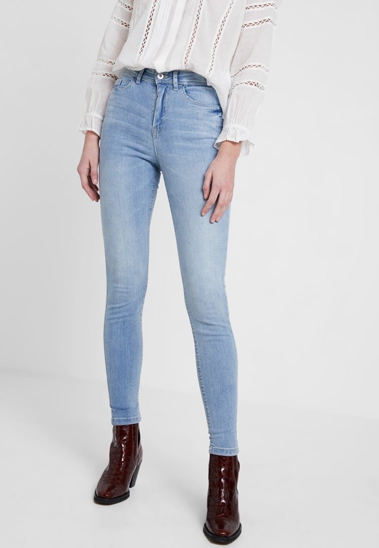 Ljusblå skinny jeans i denim, med medelhög midja och en något blekt finish. Parat med bruna klackstövlar.