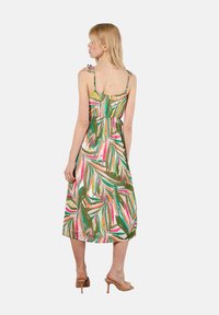 Robe midi fleurie avec des motifs de feuilles verts, roses et bruns. Dotée de fines bretelles et d'une taille cintrée. Conçue en tissu léger.