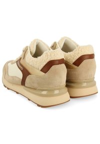 Baskets en daim beige et blanc avec des accents en fausse fourrure crème, des détails en cuir brun et une semelle en caoutchouc texturée. Éléments réfléchissants inclus.