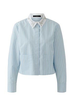 Hellblaue Bluse mit langen Ärmeln und vertikalen weißen Streifen, weißer spitzer Kragen mit silbernen Blumenmustern bestickt und verdeckten Knöpfen vorne.