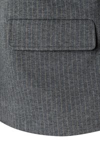 Grauer Stoff mit feinen vertikalen Streifen und einer strukturierten Oberfläche. Verfügt über eine aufgenähte, rechteckige Tasche. Akzentuiert durch dezente, hellfarbene Nähte.